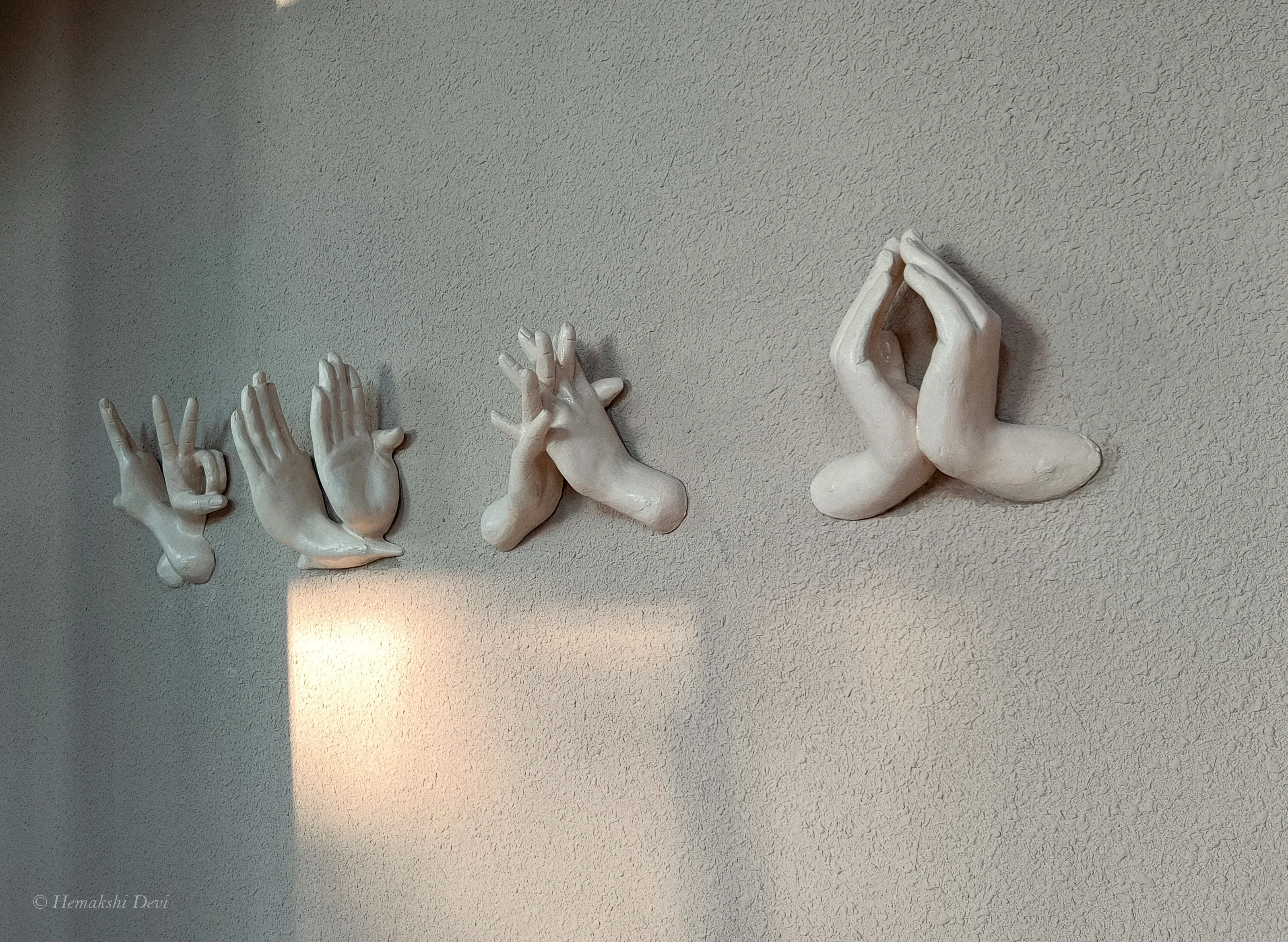 Row of hand-sculpted Sattriya dance mudra reliefs mounted along the reception corridor